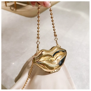 Detail of the golden lip-shaped metal evening bag with a premium gold ball chain strap
