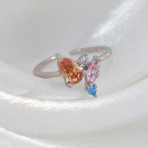 Macro view of silver ring with colorful zircons on soft white silk background