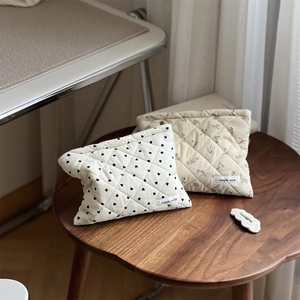 Close-up of quilted corduroy makeup bags in heart and floral prints on a wooden stool