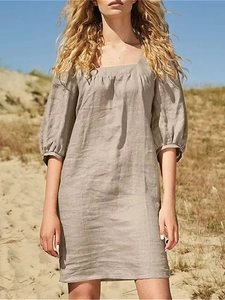 Detail of taupe linen dress featuring a French square neck and puff sleeves
