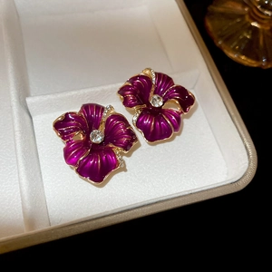 Détail de boucles d'oreilles fleurs en émail rouge avec cristaux et dorure à l'or