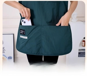 Detail of dark green apron featuring large functional pockets for phones and tools