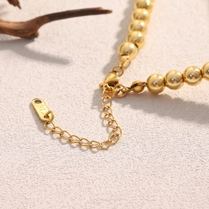 Dettaglio macro della catena a sfere placcata oro 18K con chiusura e marchio K18