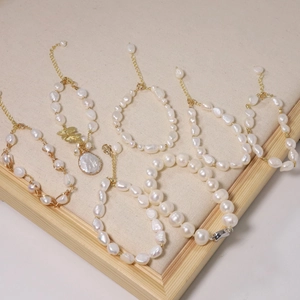 Natural pearl bracelets and necklaces with 18k gold-plated accents on a beige display