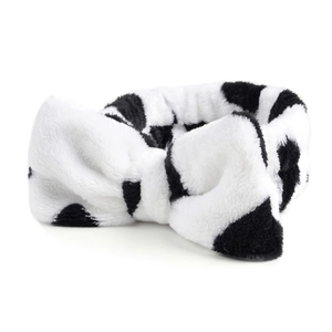 Detailopname van pluche koraalvlies hoofdband met een schattig zwart-wit stippenpatroon