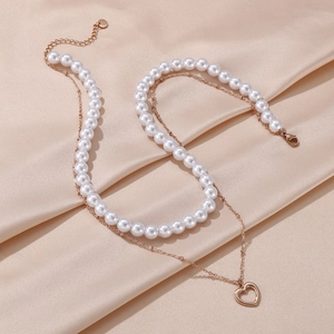 Double-layered pearl necklace with rose gold heart pendant on champagne satin background
