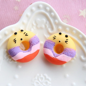 Macro shot of colorful resin donut accessories with cute facial expressions on white plate