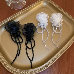 Boucles d'oreilles fleur en organza et pompons noir et blanc sur plateau doré