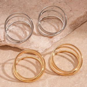 Chic silver and gold triple-layered twisted hoop earrings displayed on a textured stone