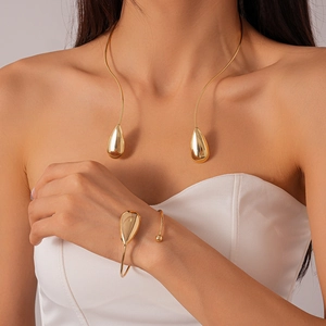 Gros plan sur le collier et le bracelet dorés en forme de larme portés par un mannequin