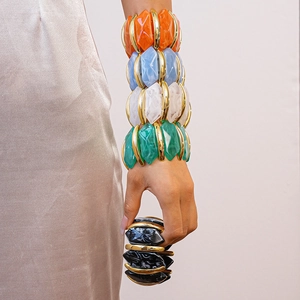 Détail de bracelets irréguliers en acrylique empilés sur le poignet avec robe en soie