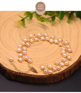 Detail of pink freshwater pearl bracelet with gold lobster clasp on wood slice base