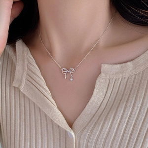 Close-up of elegant silver bow necklace with sparkling crystals on model neckline