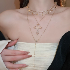 Detail view of gold layered necklace with cross and star pendants on a fashion model