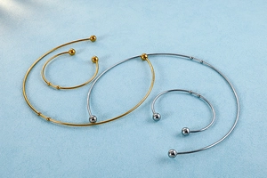 Flat lay of minimalist gold and silver open collars on a textured blue surface