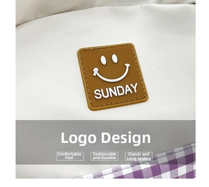 Detail of white canvas backpack featuring a brown Sunday smiley patch and purple plaid fabric