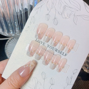 Pink French ombre press-on nails set with pearls and gold beads on a display card