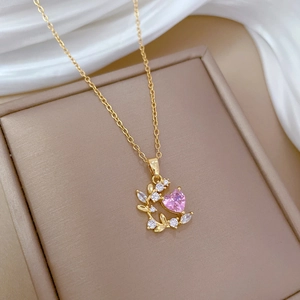 Close-up of gold heart pendant with pink stone and zircon on white silk background
