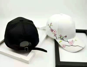 Close-up of vintage baseball caps with pink flower embroidery on black and white cotton fabric