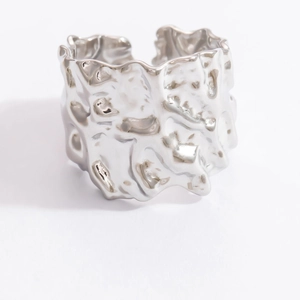 Macro detail of wide silver stainless steel ring featuring irregular lava hammer textures