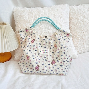 Detail of floral pattern bear print tote bag with woven rope handles on bed