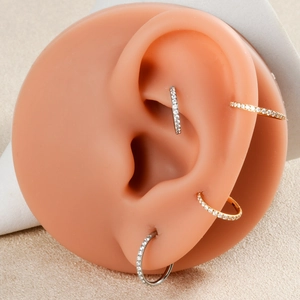 Close-up of gold and silver triple layered zircon nose rings shown on a model ear