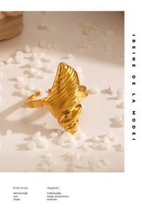 Macro detail of a golden conch-shaped open ring with textured spiral design on white stones