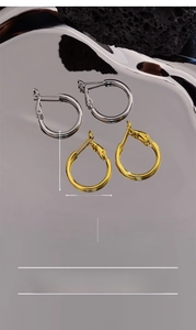 Detail of 25mm chunky hoop earrings in gold and silver finish on reflective tray