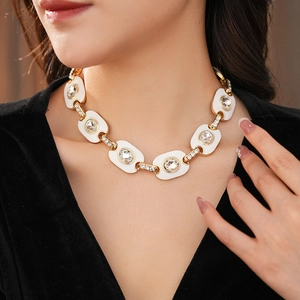 Détail d'un collier vintage doré avec émail blanc et cristaux étincelants sur un mannequin