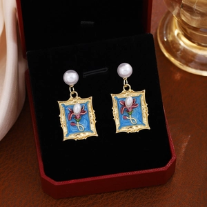 Detail of French floral earrings with pearls and blue enamel in a vintage jewelry box