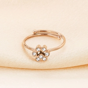 Detail of rose gold cat paw ring with sparkling cubic zirconia on beige silk