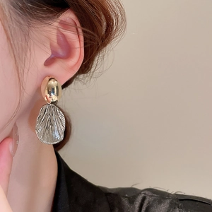 Detailed close-up of oval gold and textured silver fan-shaped metal stud earrings