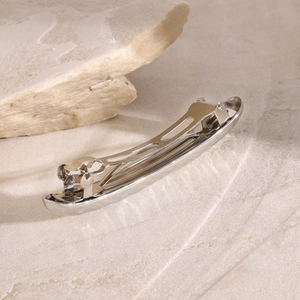 Detailed view of polished silver stainless steel spring hair clip on stone background
