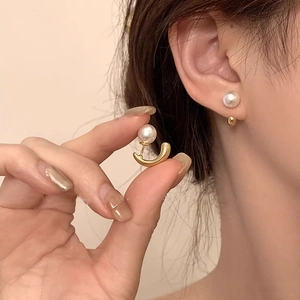 Detail of baroque freshwater pearl gold C-shaped earrings worn for a stylish look