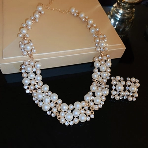 Vintage gold pearl and rhinestone jewelry set with necklace and earrings on black background