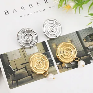 Detailed shot of silver spiral studs and gold earrings with pearls on an art magazine
