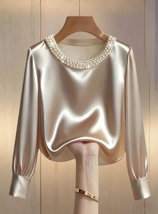Close-up of champagne satin blouse showing premium pearl neckline and silky fabric texture