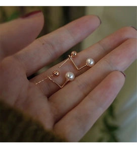 Detailed view of geometric freshwater pearl earrings in rose gold on a hand display