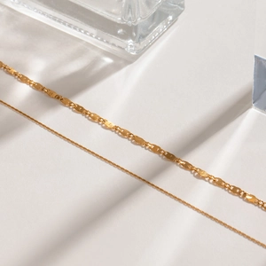 Macro detail of gold-plated stainless steel snake chain and flat link necklace layers