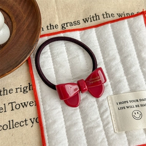 Macro detail of red acetate bow hair tie featuring a handcrafted France engraving