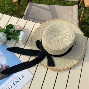 Detail of a straw boater hat with a black ribbon bow on a picnic table setting