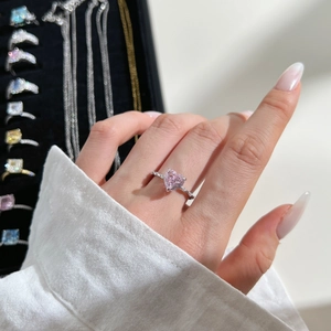 Close-up of heart-shaped pink gemstone ring with diamond-encrusted silver band