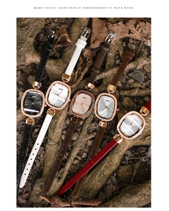 Flat lay of vintage oval women's watches with colorful leather straps on natural wood