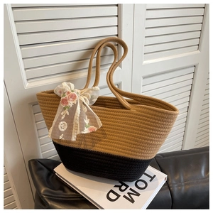 Detail of hand-woven tote bag with khaki black stitching and lace bow decoration