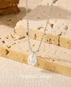 Detail of Moissanite oval pendant on S925 silver beaded chain over beige stone