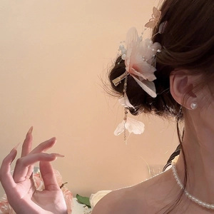 Dettaglio di fermaglio per capelli floreale con petali in rete rosa, perle e nappine