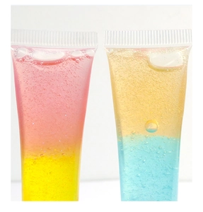 Detailed macro view of dual-color gradient lip gloss in clear tubes with shimmer effects