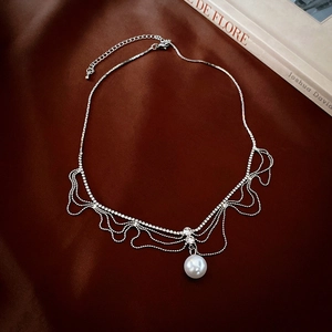 Détail du collier à franges argentées serti de strass et d'un pendentif en perle blanche