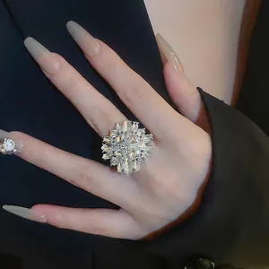 Elegant silver flower ring with sparkling crystals worn on hand over dark fabric