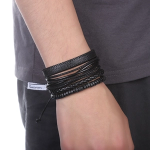 Détail d'un ensemble de bracelets multicouches en cuir tressé noir et perles